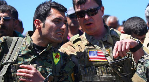 A US officer speaks with fighter from Kurdish People's Protection Units at site of Turkish air strikes near Syrian Kurdish town of Derik 